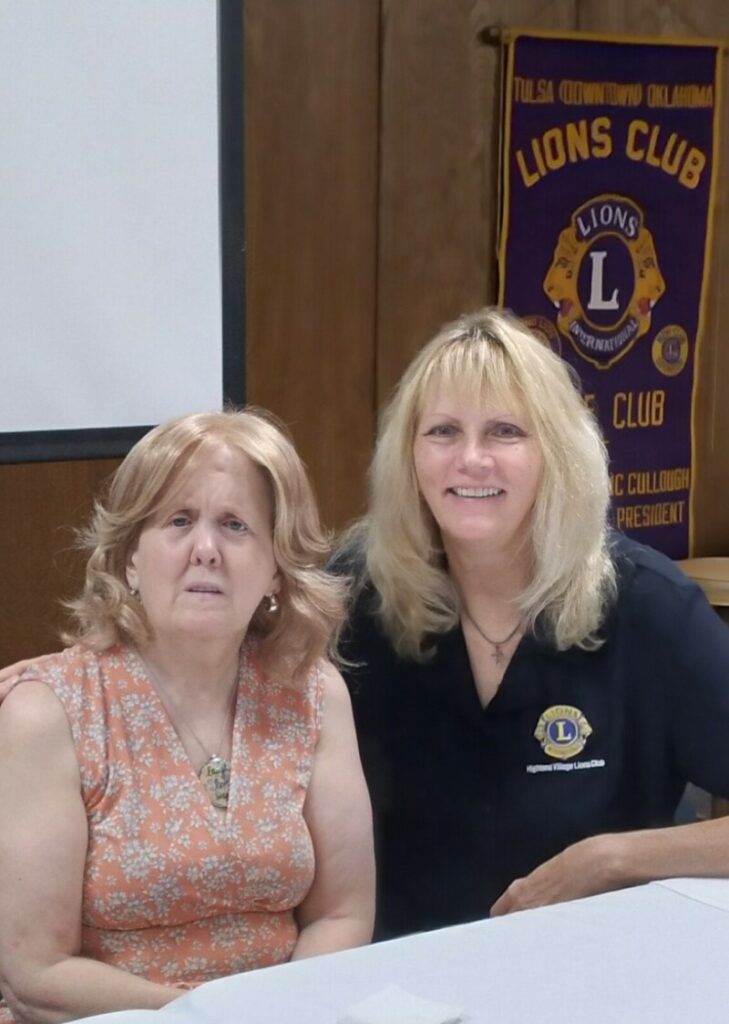 Photo of Jeri sitting at a table with Tulsa Lions member